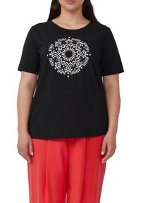 Zwarte t-shirt met korte mouwen, voorzien van een wit geometrisch patroondesign in het midden. De stof lijkt soepel en zacht.
