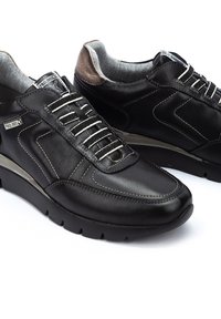 Schwarze Leder-Sneaker mit glatter Oberfläche, sichtbaren Nähten, gepolstertem Schuhkragen, silberfarbenen Schnürsenkeln und einer leichten Gummisohle.