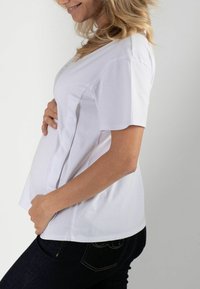 Witte zwangerschaps t-shirt van zachte katoen, met korte mouwen, een comfortabele pasvorm en een gebogen zoom, gecombineerd met donkere spijkerbroek.