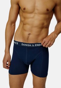 Námořnické modré boxerky s bílým pasem, na kterém se nachází text "DANISH ENDURANCE". Hladká látka, přiléhavý střih a délka po střední stehno.