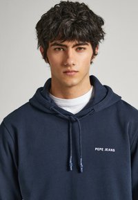 Sudadera azul marino de mezcla de algodón, con un bolsillo delantero y cordón. Logo "PEPE JEANS" bordado en blanco en el pecho.