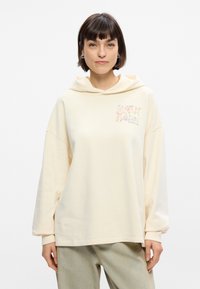 Κρέμ χρώματος φαρδύ μπουφάν με κορδόνι, που διαθέτει εκτυπωμένο σχέδιο στο στήθος. Μαλακό ύφασμα και άνετη εφαρμογή.