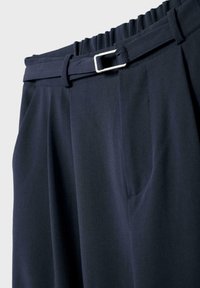 Marineblauwe broek met een gladde textuur, voorzien van een brede tailleband, een riemontwerp en voorplooien. Inclusief zijzakken voor praktisch gebruik.