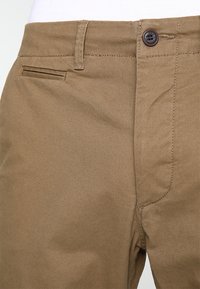 Bruine katoenmix broeken met een gladde textuur, voorzien van een knoopsluiting, een voorzak en gestikte details langs de naden.
