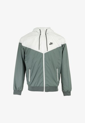 Nike windbreaker jack in lichtgrijs en groen. Bevat een capuchon, ritssluiting aan de voorkant, zijzakken, elastische manchetten en een geometrisch kleurblokontwerp.