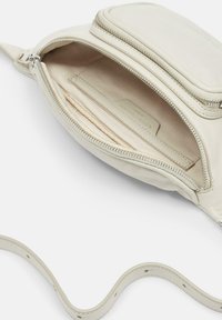 Borsa a tracolla color crema in pelle con chiusura a zip, superficie texturizzata e tracolla regolabile con fori multipli.