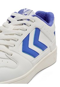 Biały sneaker z niebieskimi akcentami i wzorem w jodełkę. Posiada teksturowany materiał, płaskie sznurowadła oraz wyściełany kołnierz dla wygody.