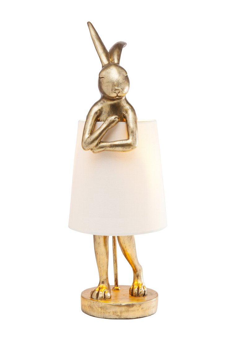 Eine goldene Kaninchenskulptur mit verschränkten Armen bildet den Sockel der Lampe, die von einem schlichten weißen Stoffschirm bedeckt ist.