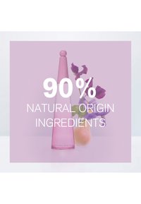Bouteille rose au design effilé et au sommet arrondi, avec une base transparente. Un texte en surimpression met en avant des ingrédients d'origine naturelle à 90%.