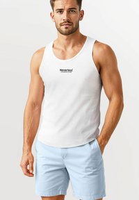 White tank top with black "Neverless Colorado River" text design, paired with light blue shorts. Smooth fabric, simple cut, casual style.