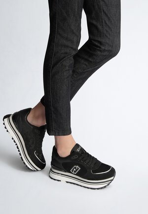 Sneaker sportive nere con tomaia testurizzata, strisce bianche sulla suola, dettagli a forma di diamante e design imbottito. Suola in gomma con motivo.