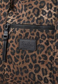 Saco de padrão de jaguar em tela castanha e preta. Apresenta fecho preto e etiqueta com o logótipo em relevo "lola berlin". Superfície texturizada com uma forma estruturada.