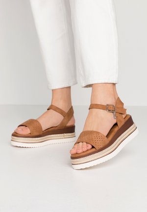 Bruine leren plateau-sandalen met geperforeerde tebanden, een verstelbare enkelband en een witte rubberen buitenzool met een houtenachtige middenzool.