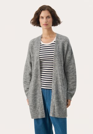 Cardigan gris de punto con frente abierto, puños acanalados y una textura suave, usado sobre una camiseta a rayas y pantalones sueltos azules.