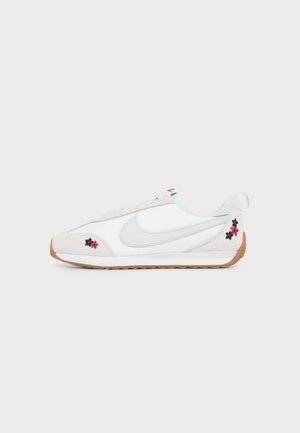 Hvid sneakers med lavt skaft, lysegrå Nike-swoosh, gummisål og lille rød og sort blomsterbroderi nær hæl og tå.