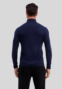 Granatowy sweter dzianinowy z teksturowanym wzorem w warkocze, dopasowany krój i wysoki kołnierz. Długie rękawy i gładkie wykończenie tkaniny.