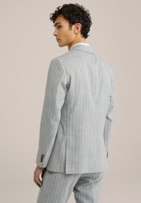Blazer a rayas gris claro, con cuello de muesca, abertura trasera y puños abotonados. La tela tiene una textura suave y un ajuste entallado.