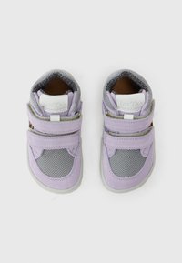 Par plitih ljubičastih i sivih dječjih cipela s dvije velcro trake na bijeloj pozadini.