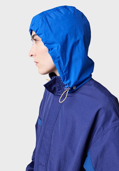 Blue hooded jacket with a drawstring. Made from lightweight fabric, featuring a zip front and a side pocket, with contrasting accent colors.