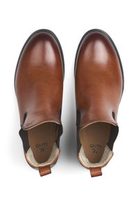 Brown leather slip-on shoes with elastic side panels, rounded toe, and textured insole, featuring a small logo inside.