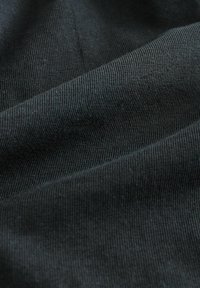 Svart stretchtextil med ribbad textur, som visar mjuka fibrer och en slät, jämn yta. Ger en närbild av tyget.