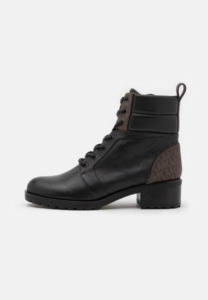 Bottine en cuir noir avec détails en tissu marron, laçage à l’avant, col rembourré, languette et petit talon bloc sur fond uni.