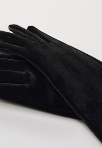 Gants en velours noir avec une texture lisse, présentant un design ajusté et des coutures renforcées au niveau des doigts.