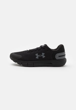 Baskets de sport noires avec tige en mesh, semelle amortissante, fermeture à lacets et logo réfléchissant Under Armour sur le côté.