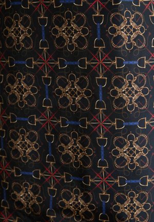 Schwarzer Stoff mit einem symmetrischen Muster aus goldenen und blauen geometrischen Formen, durchsetzt mit roten Akzenten und filigranen Details.