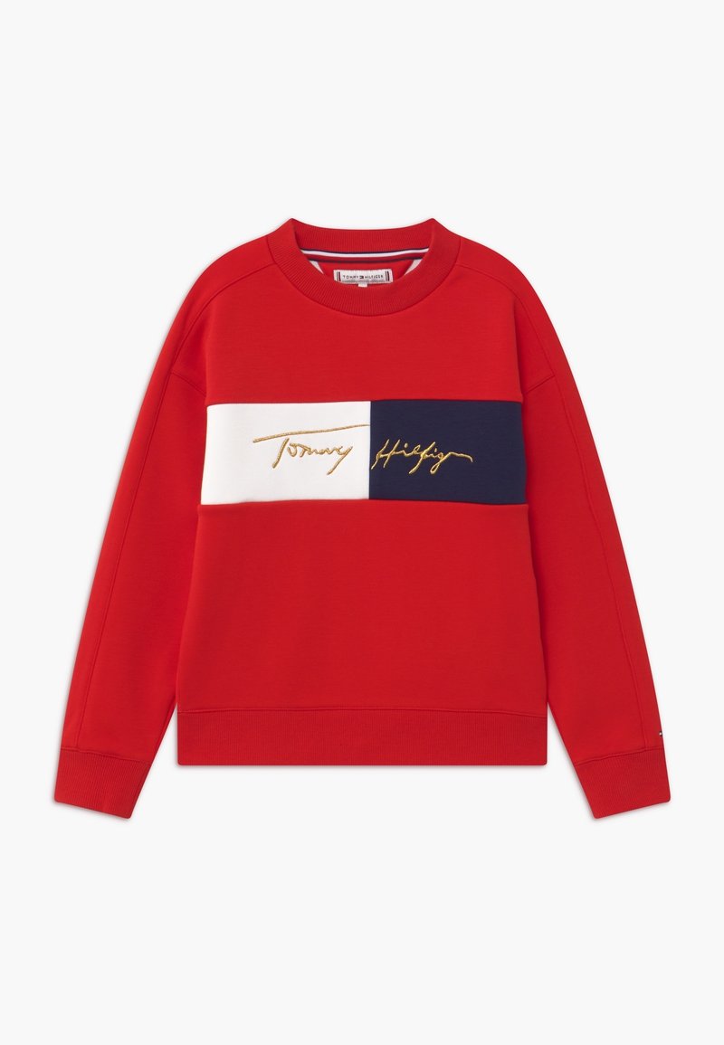 Sweatshirt rouge avec une rayure horizontale blanche et marine et broderie "Tommy Hilfiger" en doré. Tissu doux et col rond.