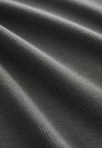 Tissu en ribbed gris avec une surface texturée, présentant de douces rides et un éclat subtil. Le matériau semble léger et flexible.