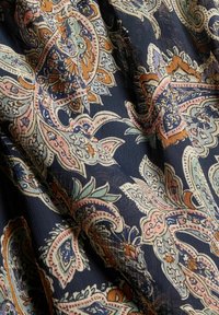 Tessuto blu navy con un intricato motivo paisley, caratterizzato da dettagli arancioni, rosa e blu. Texture morbida con una leggera lucentezza e una caduta fluida.