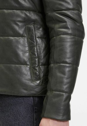 Grüne Lederjacke mit gestepptem Design, die eine seitliche Tasche und eine glatte Textur aufweist. Der Kragen ist rund, mit sichtbaren Steppnähten als Akzente.