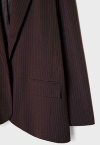 Blazer marron foncé avec de fines rayures verticales bleues. Présente un revers cranté et une poche plaquée sur le devant. Texture lisse.