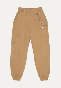 Beige cargobroek met elastische tailleband, taps toelopende boorden, steekzakken en een kettingaccessoire met een hangslotsdetail. Soepele stofstructuur.