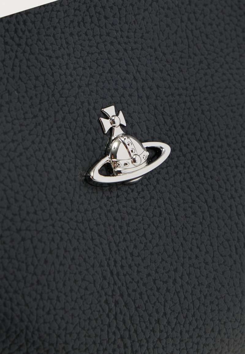 Cuir noir texturé avec une épingle décorative argentée présentant un casque et une croix dans un cadre circulaire.