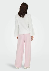 Haut blanc texturé à manches longues associé à un pantalon large à rayures rose clair, avec une coupe décontractée et une légère éclat aux manches.