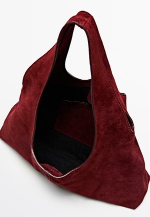 Tote bag en suède rouge avec une texture douce, grand haut ouvert, et une poche intérieure noire pour le rangement. Poignées arrondies pour un transport facile.
