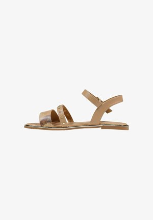 Sandalo piatto beige con tre cinturini, uno metallico con motivo floreale, uno borchiato e un cinturino alla caviglia con chiusura a fibbia.