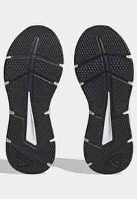 Semelles de baskets noires avec une surface texturée. Présente des motifs de semelle prononcés, une ligne d'accentuation blanche et un logo sur le talon.