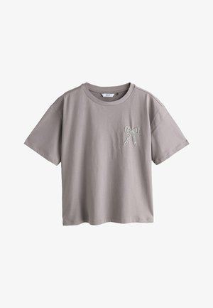 Šedé bavlněné tričko s krátkým rukávem, kulatým výstřihem a dekorativní světlou výšivkou mašle na levé straně hrudi.