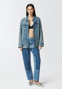 Denim jakna opuštenog kroja, s kontrastnim denim aplikacijama i kopčama na dugmad. Kombinirana s plavim trapericama s aplikacijama i metalik potpeticama.