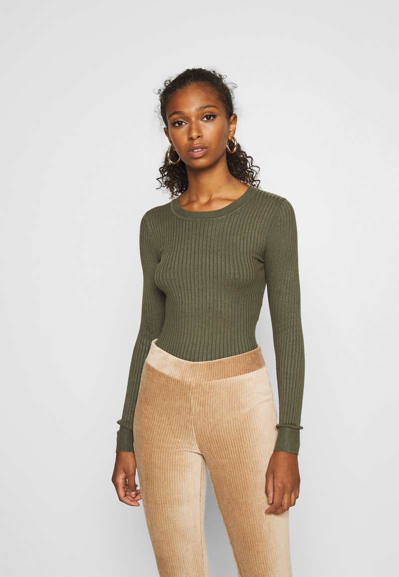 Olijfgroene geribbelde langemouwen top met een ronde halslijn, gecombineerd met beige corduroy broek met verticale textuur en een aangesloten tailleband.