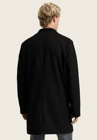 Schwarzer Mantel mit geradem Schnitt, strukturiertem Stoff und langen Ärmeln. Verfügt über ein minimalistisches Design ohne sichtbare Beschläge oder Akzente.