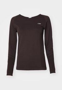 Ilgām piedurknēm brūna krekls, kas izgatavots no gludas auduma. Iespējojumi apļa formas kakla izgriezums un neliels balts logo uz krūtīm.