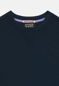 Mörkblå sweatshirt med rund halsringning och ribbade muddar. Har en liten broderad ampersand-logotyp och kontrasterande innerkrage.