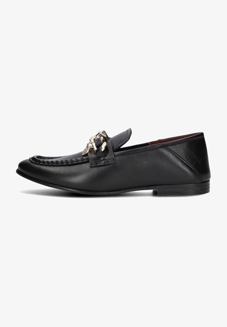 Mocassin en cuir noir avec détail de chaîne dorée, couture moc toe, et talon plat bas, vu de côté sur un fond blanc.