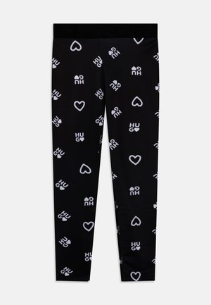 Zwarte leggings met een herhaald wit patroon van het woord "HUG" en hartvormen. Gladde textuur en elastische tailleband.