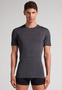 Koszulka z krótkim rękawem, okrągły dekolt w kolorze ciemnoszarym. Wykonana z miękkiego, teksturowanego materiału, dopasowany krój podkreśla sylwetkę ciała.