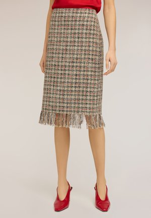 Uldblanding knælængde ternet nederdel med frynset kant båret med rød top og røde spidse slingback-højhælede sko på lys baggrund.